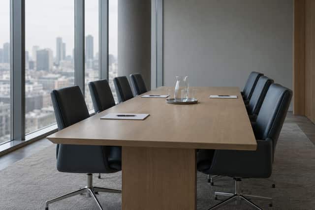 An empty conference room set for a deposition, chairs pushed in around a long table