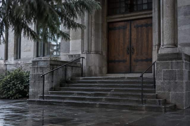 Rain-darkened stone steps and heavy timber doors of a Washington courthouse under grey skies